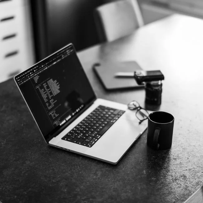 A website wireframe on a macbook screen on an office desk.